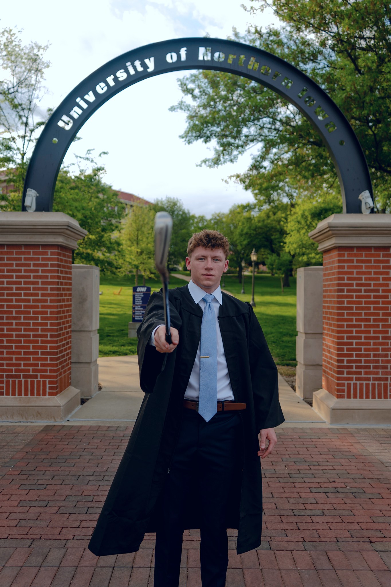 High school senior in graduation gown at the UNI arch